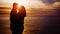 Young couple kissing on sunset towards the sea