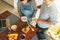 Young couple in kitchen cooking. Man is standing near table and drinking tea, his pregnant wife is standing next to him