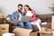 Young couple with laptop and papers sitting on sofa in room with packed boxes and discussing insurance contract after relocation i