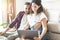 Young couple laughs and jokes while sitting on the floor browsing and shopping online with laptop - people in love search the web