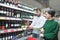 A young couple looking at a bottle of wine at a supermarket. Young couple in the alcohol department of the store