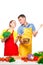 A young couple looks at each other in love while cooking vegetable salad on a white