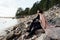 Young couple in love embracing on a sea shore. Cold autumn weather, trees in the background.