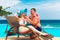 Young couple in love is enjoying cocktails at the poolside. Tropical sea in the background. Summer vacation.