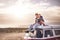 Young couple in love enjoying the travel on a vintage van during a golden sunset in a scenic place together hugging and smiling -