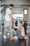 young couple in love exercise together in fitness gym . sport man boyfriend helping girlfriend to stand up or get up from floor.