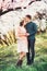 Young couple in love having a date under pink blossom trees.