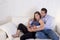 Young couple in love at home living room couch with the woman being pregnant