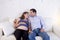 Young couple in love at home living room couch with the woman being pregnant