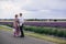 Young couple in love hugging near a lavender field on summer day. girl in a luxurious purple dress and with hairstyle with basket