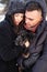 Young couple in love hugging and warm their puppy dog outdoors in in winter