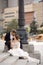 Young couple in love, lamppost, wedding suits and dress on background of old city sitting on stairs, happy wedding day together.