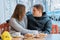 Young couple in love in outdoor cafe, spring yellow bouquet on the table, coffee, croissants