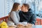 Young couple in love in outdoor cafe, spring yellow bouquet on the table, coffee, croissants