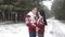 A young couple in love in red Christmas sweaters tenderly embrace in the middle of a snowy forest