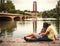 Young couple in love sitting near lake in park landscape