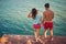 A young couple in love standing on the dock on the river bank by holding hands. Summer, love, river, romantic