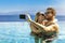 Young couple in love taking selfie in infinity swimming pool. romantic getaway, summer vacation