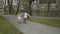 Young couple in love walking in summer park holding hands. Woman in pink tutu skirt man with longboard in hands Three