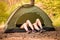 Young couple lying in tent with feet, view from outside.