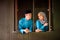 Young couple of malay muslim in traditional costume having romantic conversation during Aidilfitri celebration at wooden window of