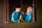 Young couple of malay muslim in traditional costume having romantic conversation during Aidilfitri celebration at wooden window of