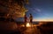 Young couple man and woman having rest at tourist tent and burning campfire on sea shore near forest