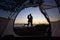 Young couple man and woman having rest at tourist tent and burning campfire on sea shore near forest