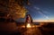 Young couple man and woman having rest at tourist tent and burning campfire on sea shore near forest