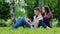 Young couple man and woman sitting on the grass in the park, enjoy the tablet. Girl pressed against the guy