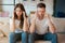 Young couple man and woman sitting on the sofa both looking tired and exhausted, grimacing mood