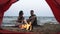 Young couple - man and woman spend time together on the beach near the fire, drinking fro the red plactic cups. Footage