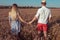 A young couple man woman, summer in wheat field, hold hands, walk and rest. Concept of love, date, emotion, tenderness