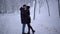 Young couple meets in a snowy park and kissing. Date of young couple. Leisure outdoors.