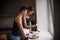 Young couple of millennials in black t-shirts hugging in the kitchen in the morning by the window