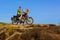 Young couple on a motorcycle on on rocky ground. Happy guy and girl travelling on a motorbike