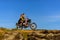 Young couple on a motorcycle on on rocky ground. Happy guy and girl travelling on a motorbike