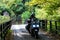 Young couple of motorcyclists riding on forest road in Zagorochoria, Greece