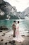 Young couple near lake Karersee, Italy. Holding hands at the stone at lake