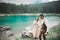 Young couple near lake Karersee, Italy. Holding hands at the stone at lake