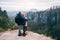Young couple in outdoor clothing with backpacks standing on plateau enjoying view of mountain ridge and wild forest in