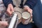 Young couple pours hot drink out of thermos, winter picnic