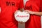 Young couple in red shirts holding white fabric heart with text