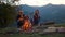 Young couple relax camp in mountains. Hiking hipsters play guitar at campfire.