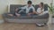 Young couple relaxing on the couch while automatic vacuum cleaner doing the housework in the living room. Household