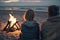 Young couple is relaxing sitting by the fire on the beach, admiring the sunset on the seashore. Ai generated