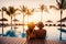 young couple relaxing in tropical resort swimming pool and enjoying the sunset. romantic summer vacation