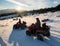 Young couple riders on four-wheelers ATV bikes on snow, enjoying sunset in the the mountains in winter