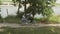 A young couple rides a tandem two-seater bike along the riverbank