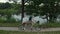 A young couple rides a tandem two-seater bike along the riverbank